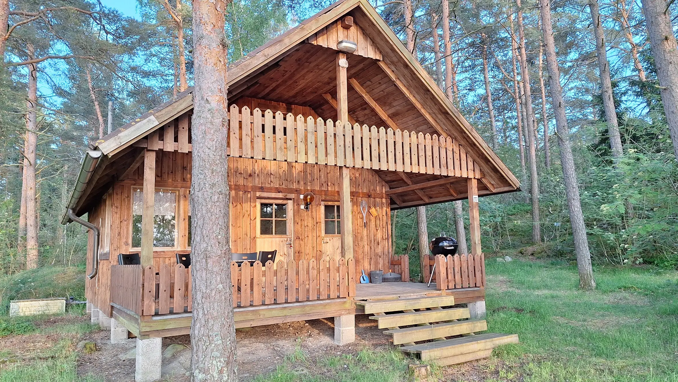 Mökki 1 edestä päivänvalossa, terassi ja grilli